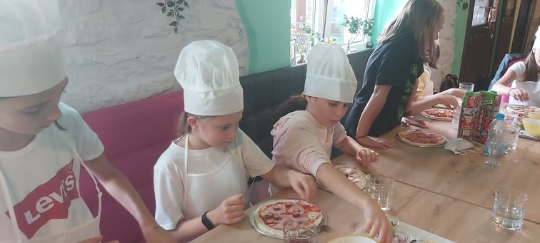 uczniowie klasy czwrtej dzielący w pizzeri pizzę na kawałki, nauka ułamków