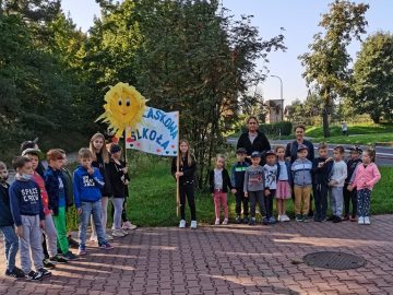 przedszkolaki i uczniowie z klucz z plakatem odblaskowa szkoła
