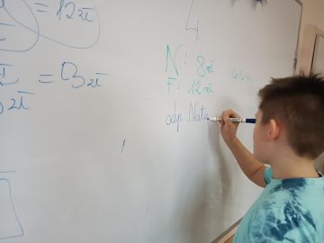 Liczący uczeń klasy czwartej przy tablicy podczas lekcji o finansach