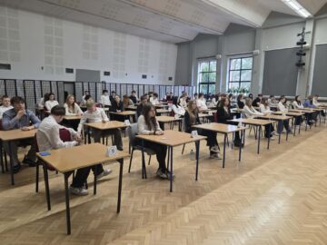 Link prowadzi do: Próbne egzaminy ósmoklasisty w naszej szkole, uczniowie piszący egzamin w auli szkolnej