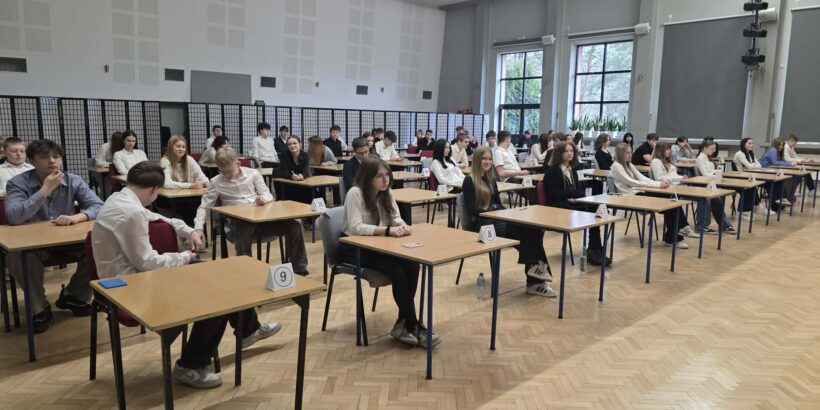 Link prowadzi do: Próbne egzaminy ósmoklasisty w naszej szkole, uczniowie piszący egzamin w auli szkolnej